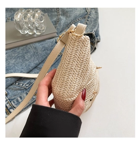 Detail of beige woven straw crossbody bag with unique triangular shape and gold hardware