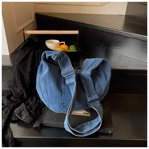 Detail of blue denim hobo bag with adjustable wide strap and silver metal buckle