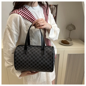 Dettaglio della borsa Boston con stampa monogramma nera e manici in pelle in un contesto lifestyle