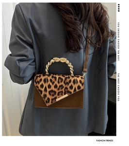 Detail of leopard print crossbody bag with golden twisted handle and irregular metal edge