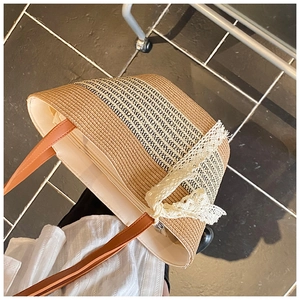 Detail of woven straw bag showing interior lining, metal zipper and lace bow accent