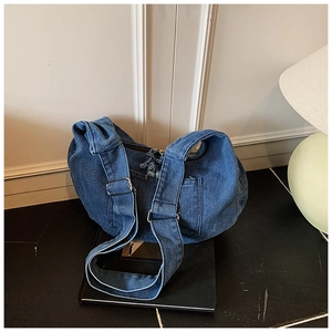 Detailed view of dark blue denim crescent bag with top zipper and adjustable shoulder strap