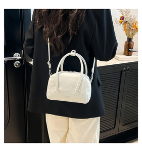 Détail d'un sac à main blanc en cuir grainé porté par un mannequin dans un intérieur chic