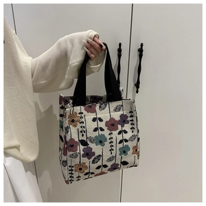 Close-up of vintage floral jacquard pattern on a white tote bag with black handles
