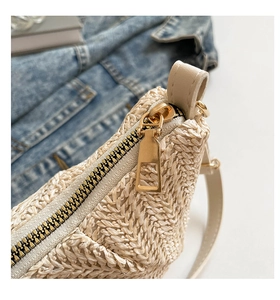 Close-up of golden metal zipper and textured beige woven material on the crossbody bag