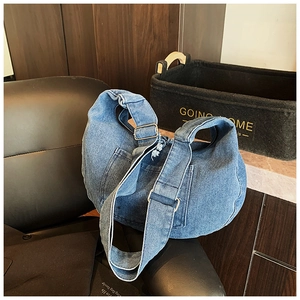 Detail of adjustable metal buckle on blue denim hobo bag with vintage wash finish