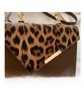 Detail showing leopard print leather texture and golden metal handle on shoulder bag