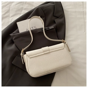 Detail of white crocodile embossed PU leather underarm bag on a gray suit jacket