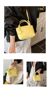 Detailed view of yellow lychee pattern bucket bag with smiley charm and adjustable strap