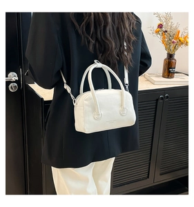 Detailed view of a white lychee grain crossbody bag worn on a shoulder in a warm setting
