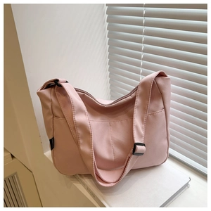 Detail of pink canvas shoulder bag featuring adjustable strap and side brand label
