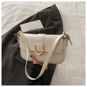 Detail of off-white croc-effect handbag with gold U-shaped magnetic clasp and strap