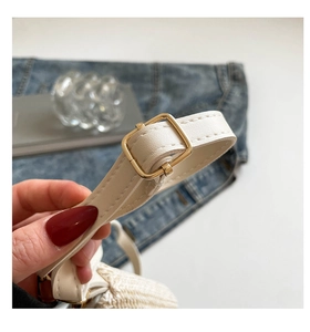 Detail of white lychee leather strap with gold buckle and stitching on a woven bag