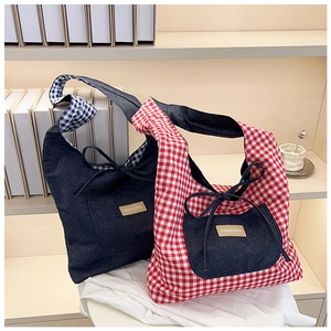 Detail of denim and red plaid tote bags with drawstring bows and leather tags