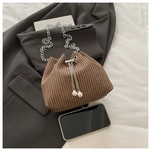 Détail du sac seau marron tressé avec bandoulière chaîne argentée et cordon à perles