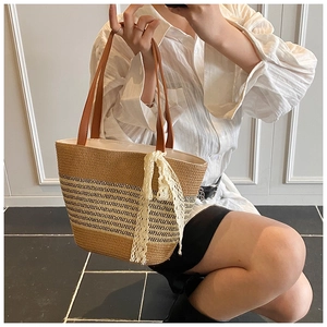 Detail of woven straw tote bag with elegant white lace ribbon and leather handles