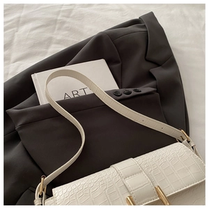 Detail of white crocodile texture leather shoulder bag with elegant gold metal buckle