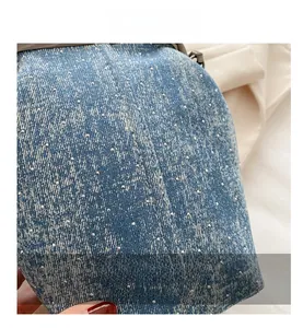 Close-up of blue denim fabric with sparkling silver rhinestones and detailed stitching