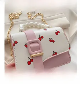 Detail of a pink and white cherry print mini bag with pearl handle and gold chain strap