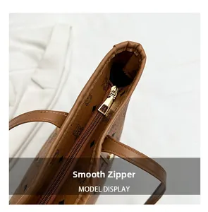 Close-up of smooth gold metal zipper and bear print on brown leather tote bag