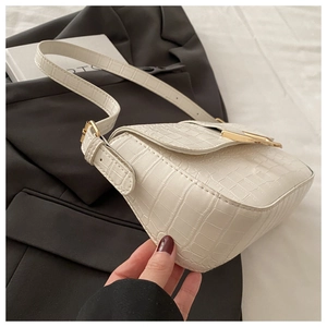 Detail of white crocodile embossed leather underarm bag with gold metal buckle closure