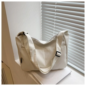 Detail of white nylon tote bag with front pocket and adjustable strap in minimalist setting