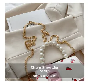 Close-up of white crossbody bag with cherry prints, pearl handle and gold chain strap