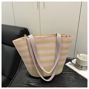 Detail of pink and beige striped woven tote bag with thick fabric handles on a dark table