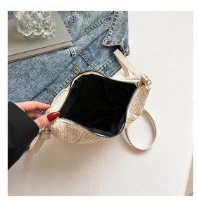 Detail of beige woven crossbody bag showing interior black lining and zipper closure