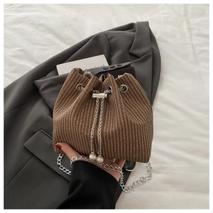 Détail d'un sac seau tressé marron avec cordons à perles et bandoulière chaîne argentée