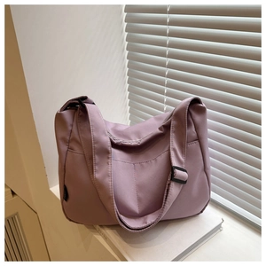 Detail of mauve nylon tote bag on a white windowsill showing side pocket and strap