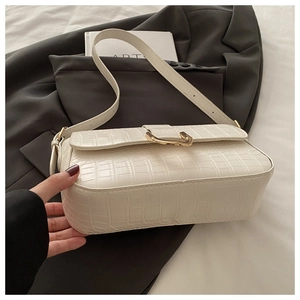 Detail of crocodile embossed cream PU leather underarm bag with gold metal buckle closure