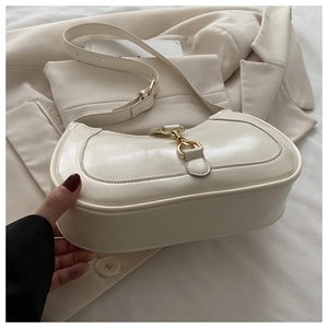 Détail d'un sac hobo crème avec fermoir piston doré vintage et texture cuir lisse
