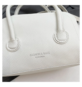 Detail of white lychee grain leather handbag with Fashion and Bags embossed text
