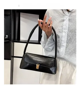 Close-up of black glossy leather baguette bag featuring a stylish gold metal buckle