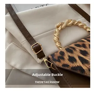 Detailed macro of leopard print handbag with golden metallic handle and adjustable buckle