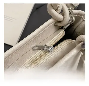 Detailed macro view of silver metal zipper and textured lychee grain leather on beige handbag
