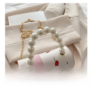 Detail of white leather barrel bag with cherry print and faux pearl handle accent