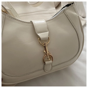 Détail d'un sac à bandoulière en cuir blanc crème avec un fermoir mousqueton doré chic