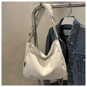 Detail of white nylon tote bag with V-shaped stitching and wide strap on casual display