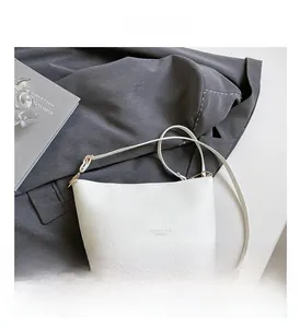 Vue détaillée du cuir blanc texturé litchi avec ferrures dorées sur le sac à main chic