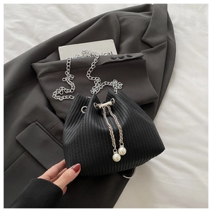 Détail d'un sac seau noir tressé avec bandoulière chaîne et cordon orné de perles