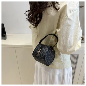 Detail view of retro mini barrel bag featuring grey M-pattern print and gold chain strap