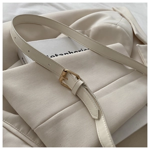 Gros plan sur la bandoulière réglable en cuir PU crème avec boucle en métal doré clair