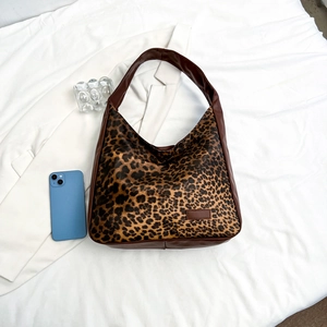 Sac cabas léopard rétro avec poignées en cuir marron posé sur un blazer blanc