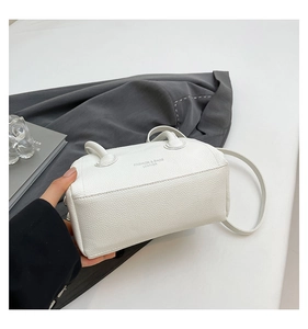 Detailed close-up of white lychee pattern leather handbag with fashion text and strap