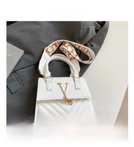 Detailed macro view of white quilted bag with metal V-logo and printed wide shoulder strap