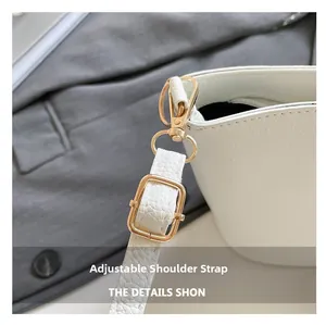 Détail de la bandoulière réglable avec boucles dorées sur le sac seau blanc grainé