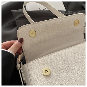 Detail of white crocodile-embossed PU bag showing golden magnetic snap closure and lining