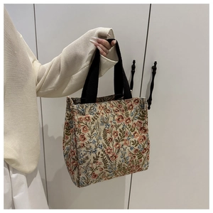 Close-up of vintage floral jacquard tote bag with black strap held by model